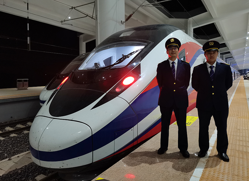 劉銀能（右一）與中國師父鄔俊鴻在動車組前合影。受訪者供圖